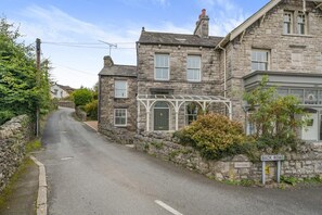 A narrow street with stone buildings, a covered porch, and a 'BACK ROAD' sign. - 3 Bed in Lindale (oc-p33519) (Lindale)