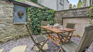 Un mur de pierres, une table en bois et des chaises, le tout dans un cadre de jardin.