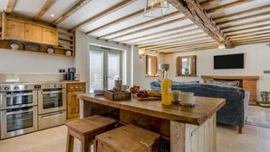Una cucina con travi in legno, un'area pranzo con sgabelli, un divano e un camino.