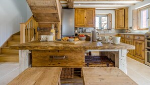 Una cucina rustica con travi in legno, un'isola centrale con lavello e pensili in legno.