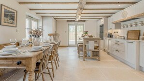 Een ruime keuken met witte kasten, een houten eettafel gedekt voor zes personen, en een groot raam dat zorgt voor natuurlijk licht.