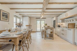 A spacious kitchen with white cabinetry, a wooden dining table set for six, and a large window providing natural light. - 4 Bed in Moccas (oc-r33127) (Moccas)