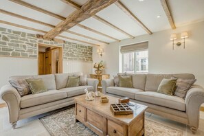 A cozy living room with two sofas, a wooden coffee table, stone walls, exposed wooden beams, and a window with blinds. - 4 Bed in Moccas (oc-r33127) (Moccas)