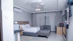 Habitació d'hotel moderna amb llit, sofà, escriptori i televisió.