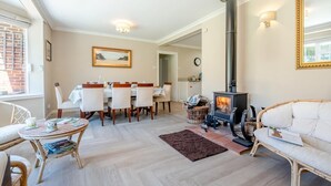 A cozy living room with a fireplace, dining area, and a view of the outside.