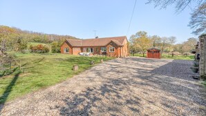 A brick house with a gravel driveway and a small shed.