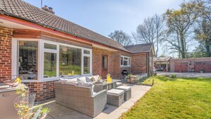 A house with a patio, a brick exterior, and a large window overlooking a garden.
