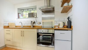 Eine moderne Küche mit Mikrowelle, Backofen und Kühlschrank, Holz Arbeitsplatten und einem Fenster über der Spüle.