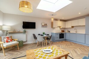 A modern apartment with a dining area, kitchen, and a living space with a large window and ceiling light.