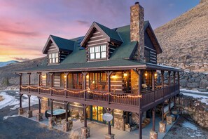 Un chalet doté d’une façade en pierre, d’une terrasse en bois et d’un balcon agrémenté de guirlandes lumineuses.