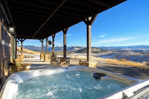 Un bain à remous sous une pergola en bois, avec vue sur la montagne.