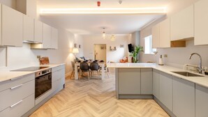 A modern kitchen with a central island, a dining area with a table and chairs, and a living space with a sofa and a TV. - 3 Bed in Shanklin (oc-h33403) (Shanklin)