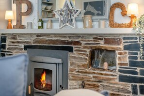 A stone fireplace with a visible fire, a decorative star, and a letter 'P' sign. - 2 Bed in Padstow (oc-p00572) (Padstow)