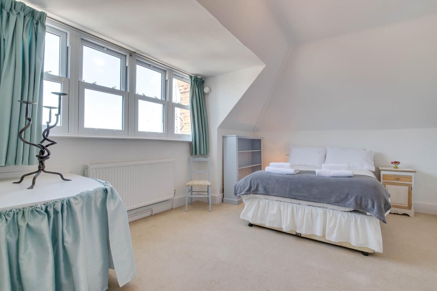 Une chambre à coucher avec un lit, une chaise, une table et un radiateur.