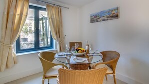 A dining area with wicker chairs, a glass table, and a bowl of fruit. - 2 Bed in Torquay (oc-babbme) (Torquay)