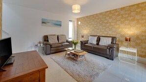 A living room with two sofas, a coffee table, a TV, and a lamp. - 2 Bed in Torquay (oc-babbme) (Torquay)