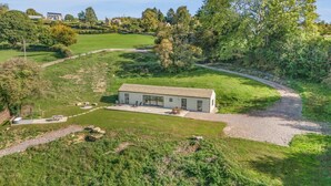 Een modern huis met een ruime patio, omgeven door weelderig groen en een kronkelend pad.