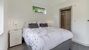 Een slaapkamer met een bed, nachtkastjes, een raam en een deur naar een badkamer.