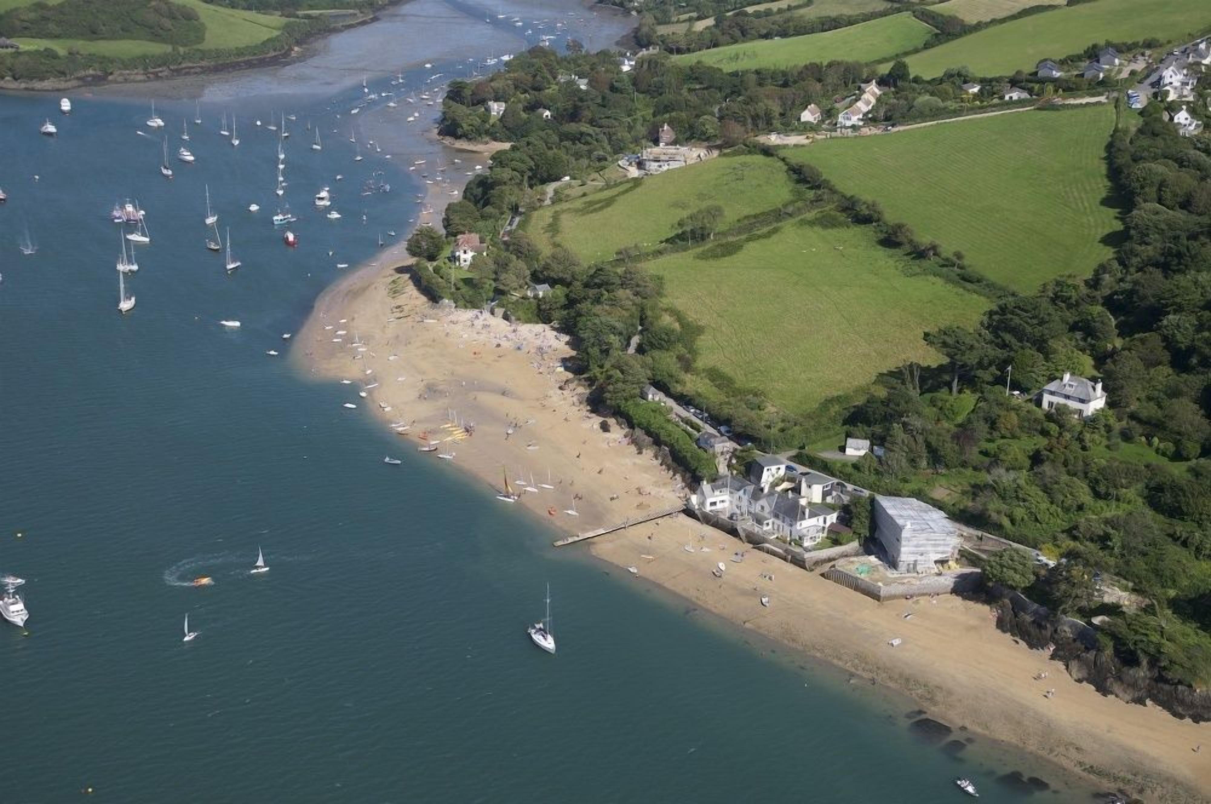 An aerial view of a coastal area with a sandy beach, boats, and houses.