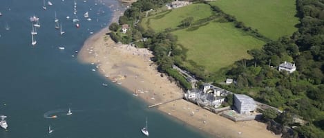 An aerial view of a coastal area with a sandy beach, boats, and houses.
