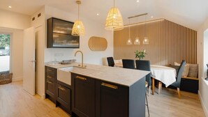 A modern kitchen with dark cabinetry, a central island, and pendant lighting. - 4 Bed in Lobb (oc-s33517) (Lobb)