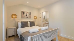 A modern bedroom with a white bed, two bedside tables, a large mirror, and a painting on the wall. - 4 Bed in Lobb (oc-s33517) (Lobb)