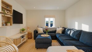 A modern living room with a sectional sofa, a flat-screen TV, and a large window with a view. - 4 Bed in Lobb (oc-s33517) (Lobb)