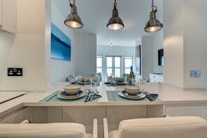 Una cocina moderna con una isla central, iluminación colgante y vistas al área de comedor.