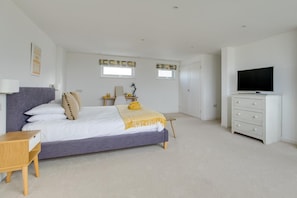 A bedroom with a bed, bedside table, dresser, TV, and two windows. - 6 Bed in Constantine Bay (oc-p00571) (Constantine Bay)
