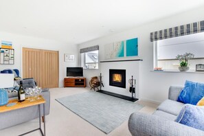A modern living room with a fireplace, a television, and a sofa. - 6 Bed in Constantine Bay (oc-p00571) (Constantine Bay)