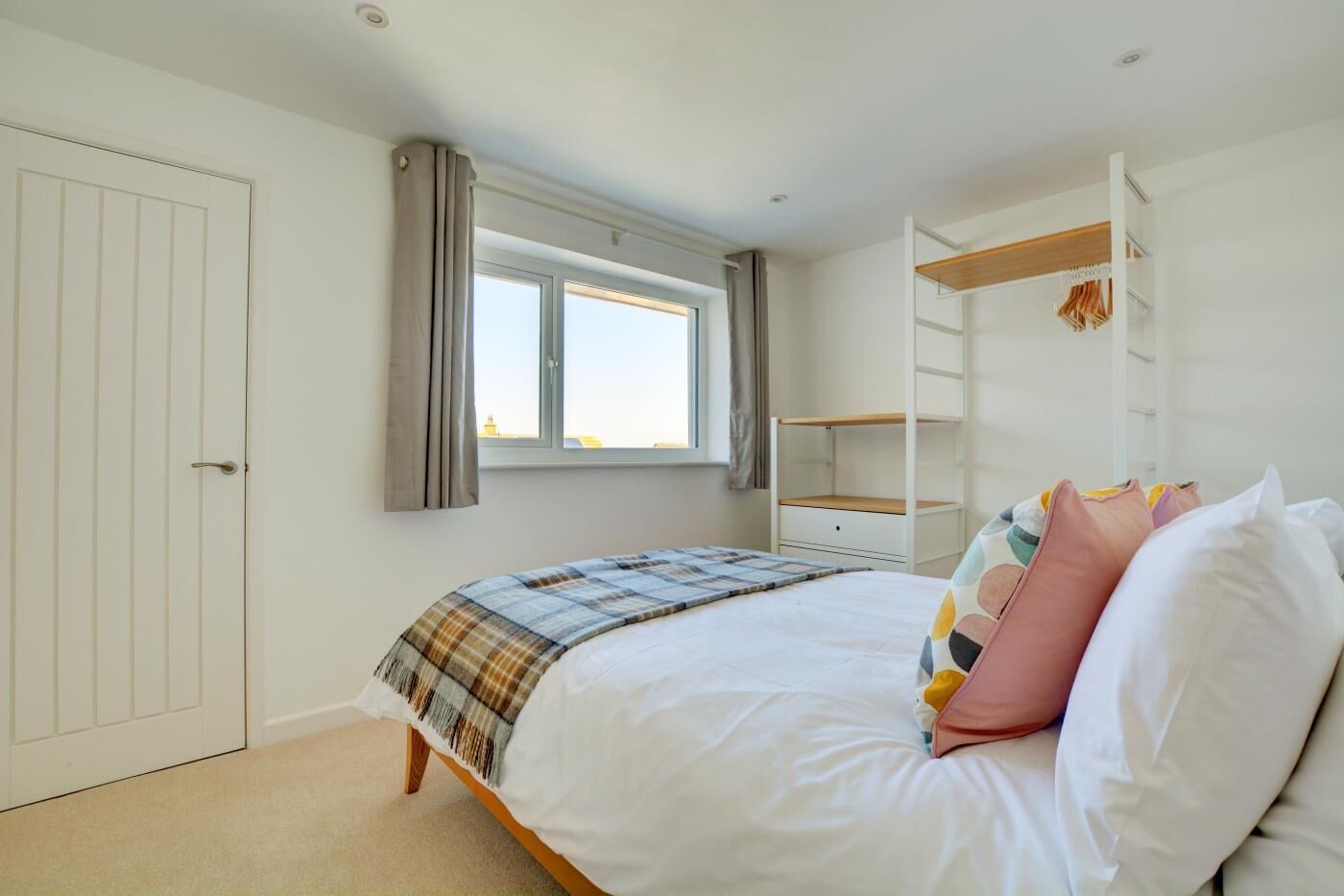 Une chambre à coucher comprenant un lit, une fenêtre, une armoire et une étagère intégrée.