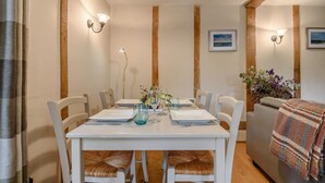 A dining area with a white table set for four, surrounded by white chairs with woven seats. - 2 Bed in Rumburgh (oc-dgf) (Rumburgh)