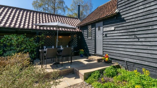 A patio with outdoor seating and a wooden building with a tiled roof. - 2 Bed in Rumburgh (oc-dgf) (Rumburgh)
