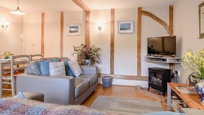A cozy living room with a grey sofa, wooden beams, a television, and a fireplace. - 2 Bed in Rumburgh (oc-dgf) (Rumburgh)
