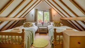 A cozy attic bedroom with two wooden beds, a small table, and a window with curtains. - 2 Bed in Rumburgh (oc-dgf) (Rumburgh)