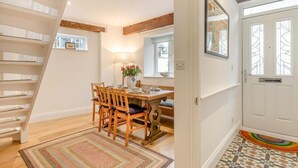 A dining area with a wooden table and chairs, a lamp, and a view of the outside through a window. - 2 Bed in Lynton (oc-s33456) (Lynmouth)