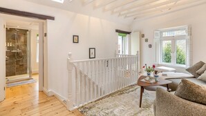 A spacious room with a wooden floor, a white railing, a large window, and a door leading to a shower area. - 2 Bed in Lynton (oc-s33456) (Lynmouth)