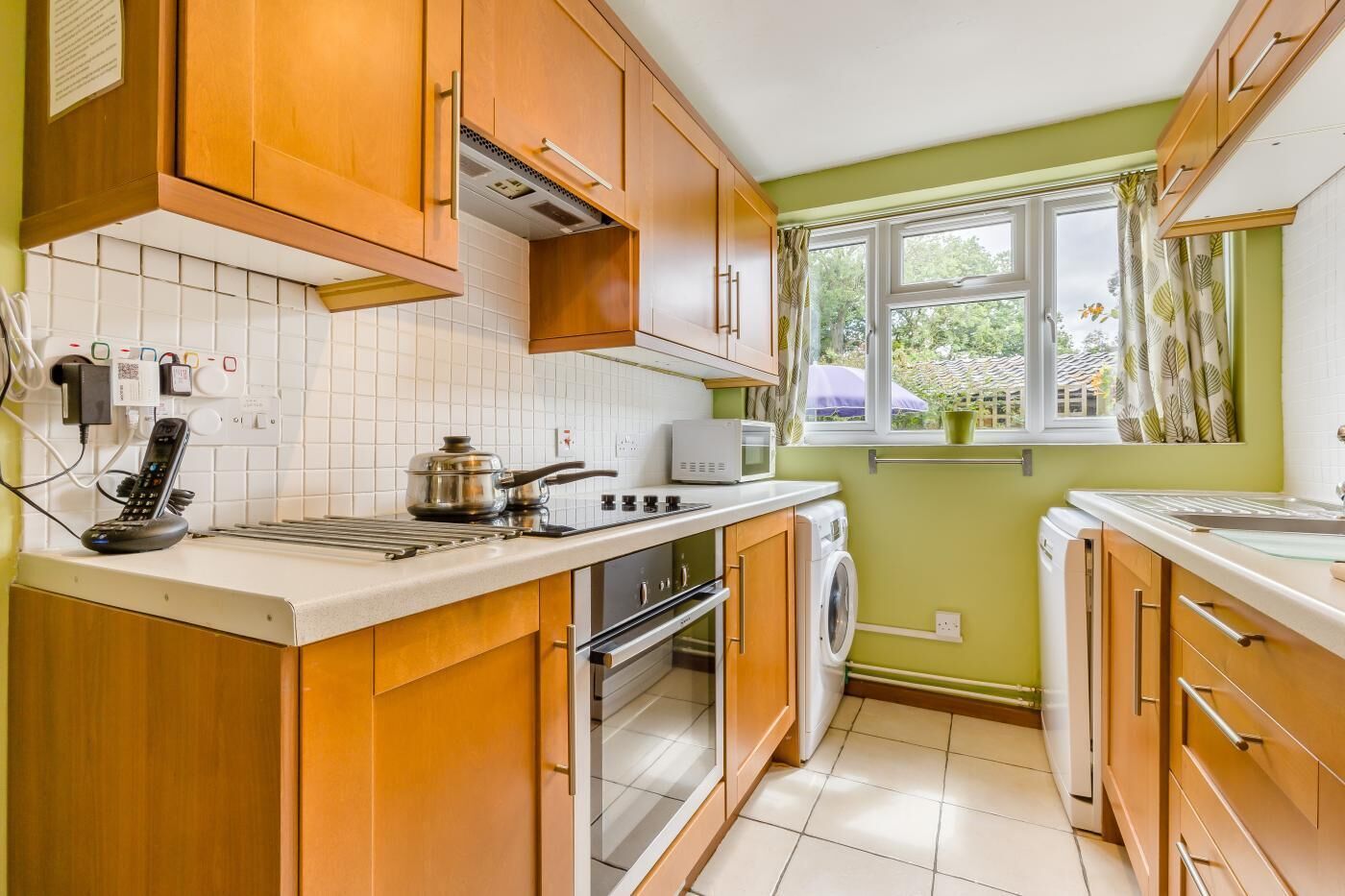 A kitchen with wooden cabinets, a microwave, a stove, and a washing machine.