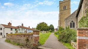 A narrow pathway leading to a church with a tall tower, surrounded by traditional houses and a stone wall. - 2 Bed in Reepham (oc-1755) (Reepham)