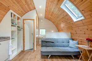 A cozy room with a loft bed, a small table, and a built-in shelf unit.