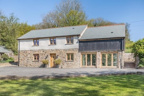 A two-story stone house with a grey roof, a wooden door, and large glass windows. - 3 Bed in North Molton (oc-o33357) (North Molton)