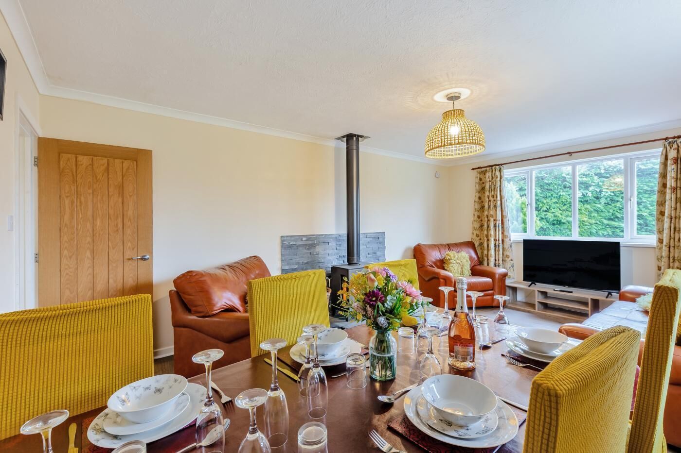 A living room with a dining area set for a meal, featuring a sofa, chairs, a TV, and a fireplace.