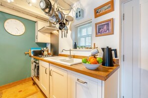 A kitchen with white cabinets, a wooden countertop, a sink, and a bowl of fruit. - 2 Bed in Whitby (oc-w134) (Whitby)