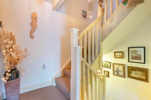 A staircase with a white railing, a vase with dried flowers, and framed pictures on the wall. - 2 Bed in Whitby (oc-w134) (Whitby)