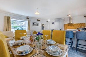 A dining area with yellow chairs, a table set for four, and a kitchen in the background.