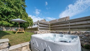 Tinaco en un patio trasero con muros de piedra, una mesa de picnic y una terraza de madera.