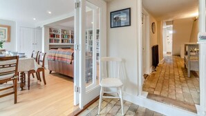 Ein gemütlicher Wohnbereich mit Esstisch, Stühlen, einer Couch und einem Bücherregal.