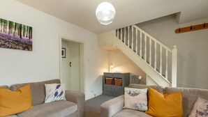Ein Wohnzimmer mit zwei Sofas, einer Treppe, einem Wandbild und einem Schrank.