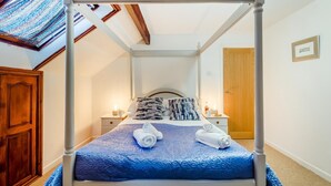 Ein Himmelbett mit einer blauen Bettdecke, zwei Kissen und zwei aufgerollten Handtüchern.