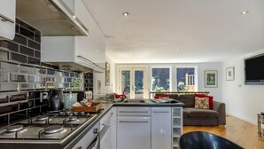 Een moderne keuken met een centraal eiland, een zithoek met een bank en een groot raam met uitzicht op de omgeving.
